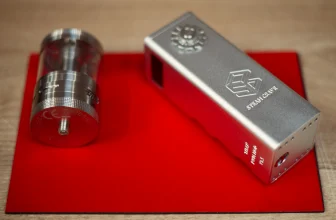 A silver vape mod and vape tank laying next to each other on a red matt.